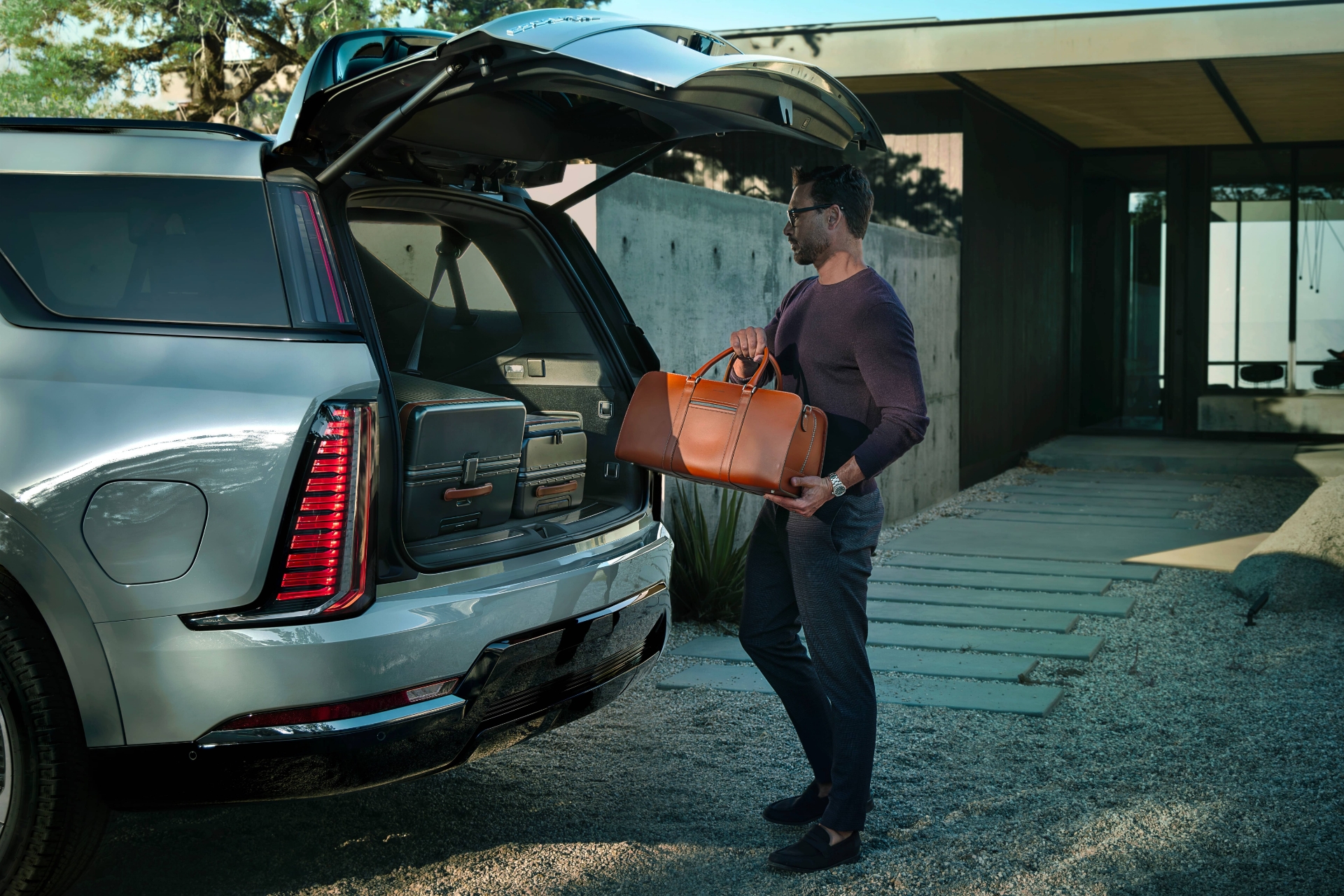 یک مرد درحال گذاشتن چمدان در صندوق عقب خودرو کادیلاک